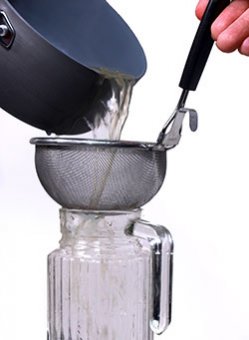 Pouring green coffee extract through a sieve to eliminate the coffee beans